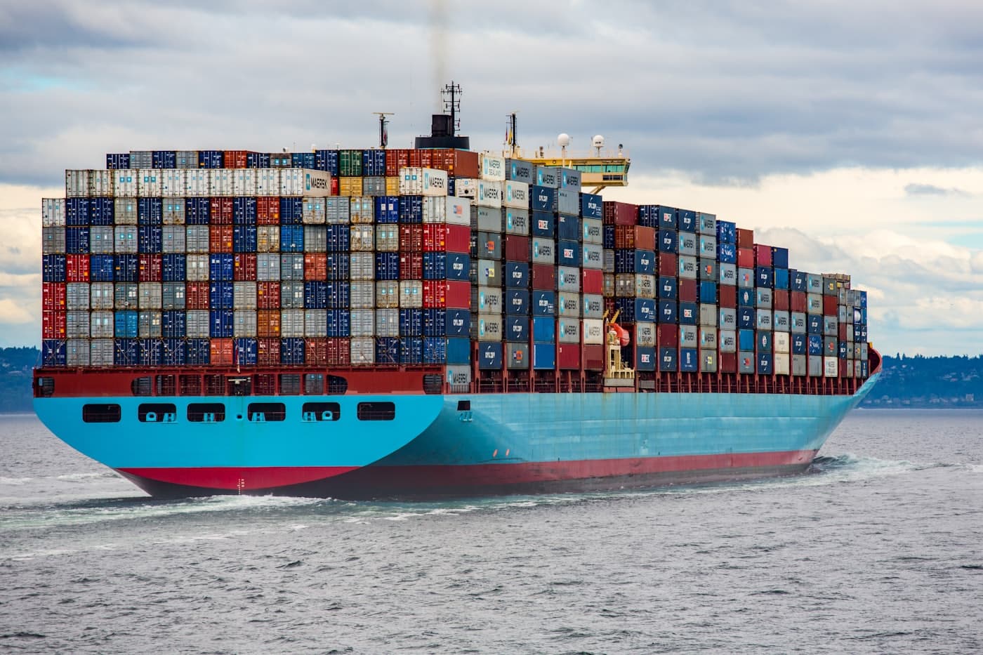 Containers stacked in rows across the deck of a vessel under way.